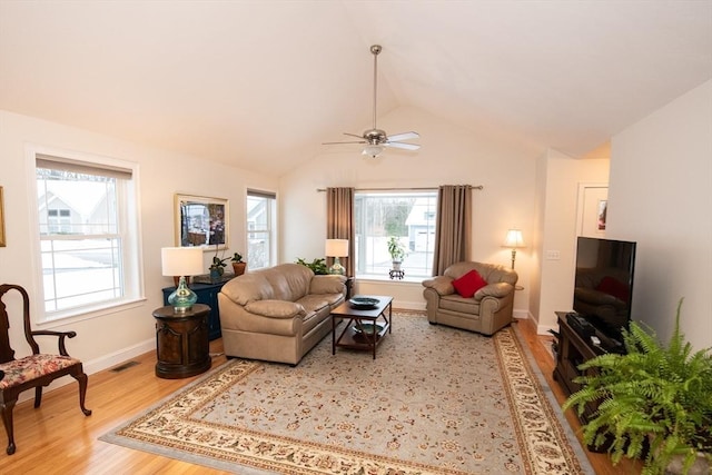 living area with visible vents, light wood-style floors, baseboards, ceiling fan, and vaulted ceiling