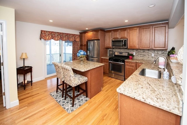 kitchen with a center island, decorative backsplash, light wood-style flooring, stainless steel appliances, and a sink