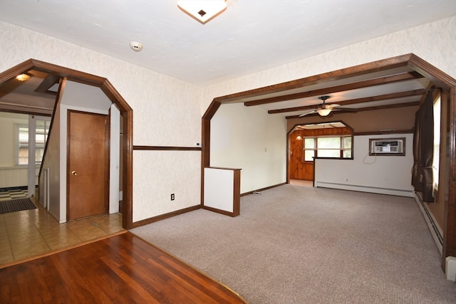 spare room with an AC wall unit, beamed ceiling, hardwood / wood-style floors, a baseboard radiator, and ceiling fan