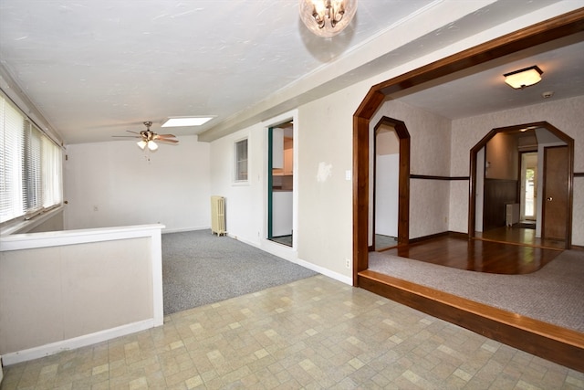 interior space with a skylight, ceiling fan, carpet flooring, and radiator