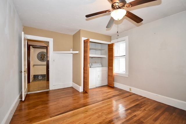 unfurnished bedroom with a closet, wood-type flooring, washer and clothes dryer, and ceiling fan