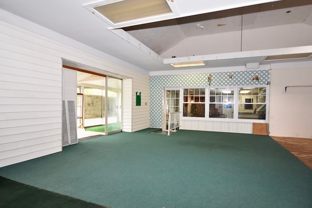 unfurnished living room featuring carpet and vaulted ceiling