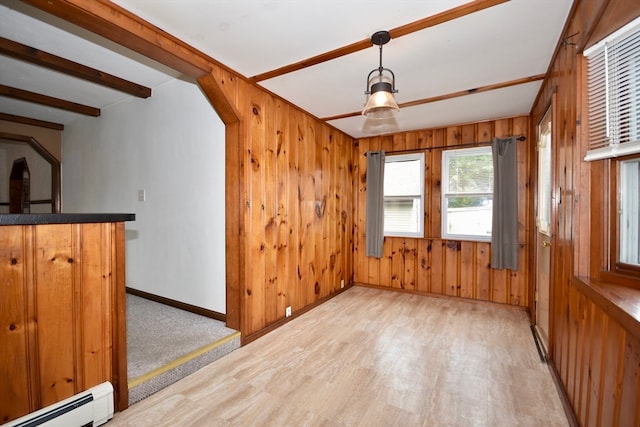 empty room with baseboard heating, beamed ceiling, wooden walls, and light wood-type flooring