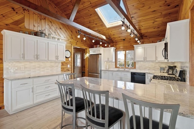 10 Chadwell Ave, Sandwich, MA 02563 - kitchen with wooden walls, vaulted ceiling with skylight, and stainless steel appliances