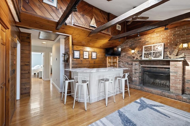 10 Chadwell Ave, Sandwich, MA 02563 - kitchen with a ceiling fan, wood finished floors, wood walls, vaulted ceiling with beams, and a brick fireplace