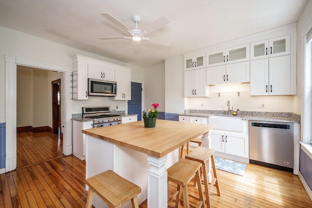 kitchen featuring appliances with stainless steel finishes, a sink, wooden counters, and light wood-type flooring