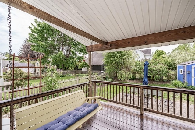 wooden deck with a fenced backyard, an outbuilding, and a storage unit