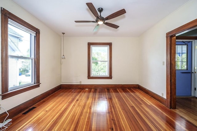 empty room featuring hardwood / wood-style floors, baseboards, a ceiling fan, and ornamental molding