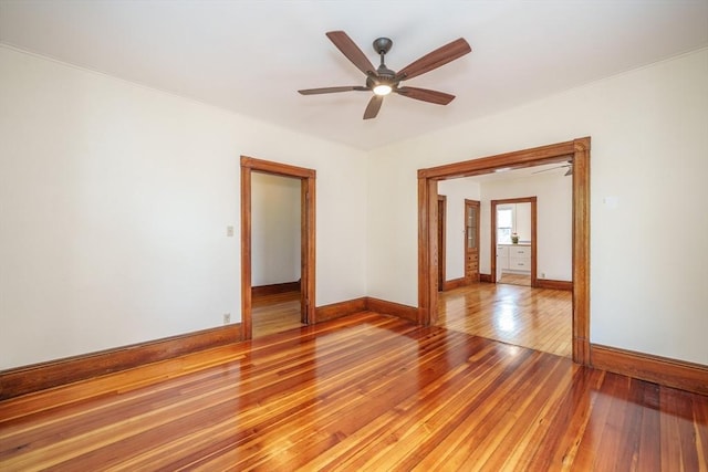 spare room with baseboards, light wood-style flooring, and a ceiling fan