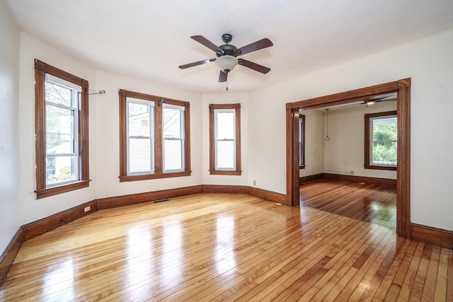 spare room with light wood-style flooring, a ceiling fan, and baseboards
