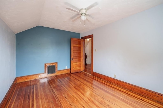spare room featuring baseboards, ceiling fan, wood finished floors, and vaulted ceiling