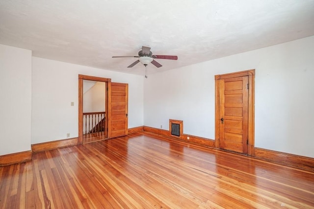 spare room featuring light wood-type flooring, baseboards, ceiling fan, and radiator