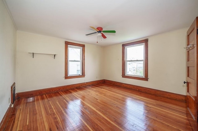 unfurnished room with plenty of natural light, hardwood / wood-style flooring, ceiling fan, baseboards, and crown molding