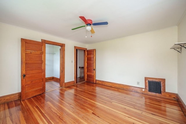 unfurnished bedroom with light wood-style flooring, baseboards, a ceiling fan, and crown molding