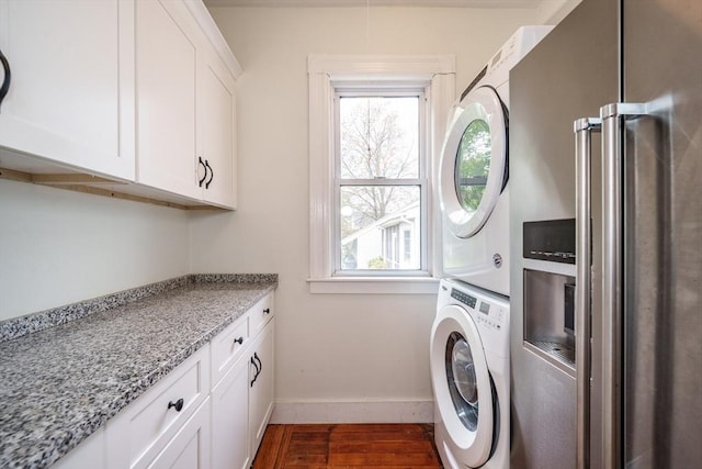 washroom with stacked washer and clothes dryer, dark wood-type flooring, healthy amount of natural light, and baseboards