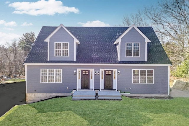 new england style home featuring a front lawn and roof with shingles