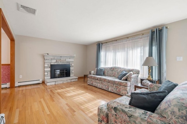 living room featuring a fireplace, a baseboard radiator, wood finished floors, and visible vents