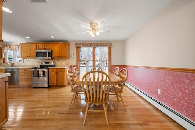 dining room with a baseboard heating unit, light wood-type flooring, ceiling fan, and recessed lighting