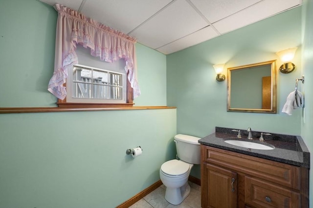 bathroom with baseboards, toilet, tile patterned floors, vanity, and a paneled ceiling