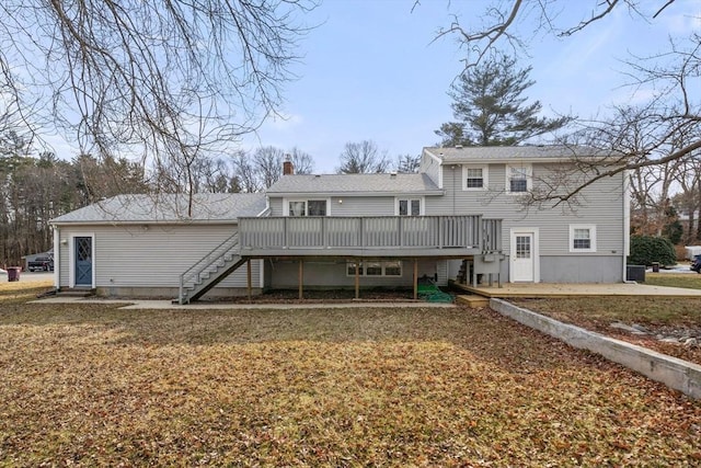 rear view of house featuring a deck, a chimney, a yard, and stairway