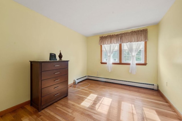 bedroom with a baseboard radiator, baseboards, and light wood finished floors