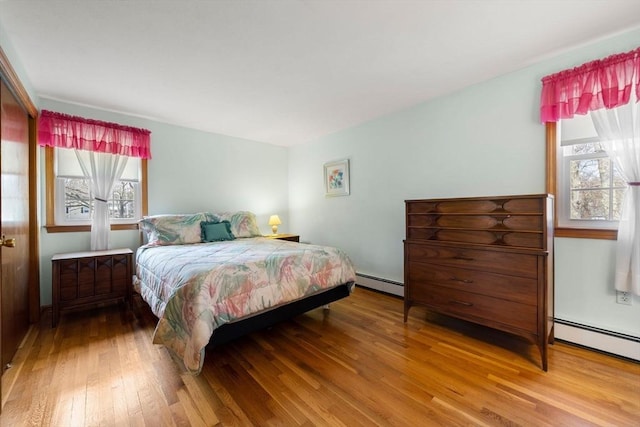 bedroom with wood-type flooring and a baseboard heating unit