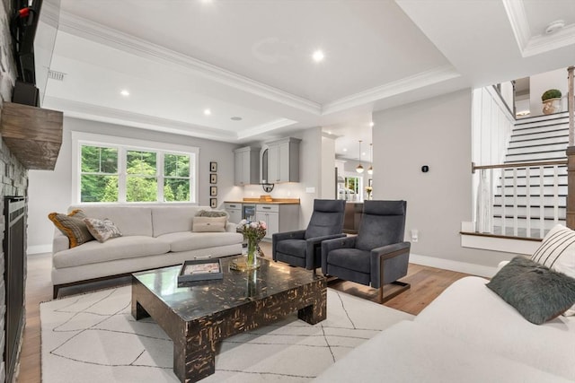 35 E St, Middleton, MA 01949 - living room with light wood-style floors, ornamental molding, a raised ceiling, a stone fireplace, and stairway