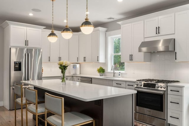 35 E St, Middleton, MA 01949 - kitchen with appliances with stainless steel finishes, wall chimney range hood, a kitchen island, light countertops, and a kitchen bar