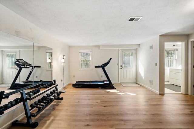 workout area featuring washer / clothes dryer, visible vents, and light wood finished floors