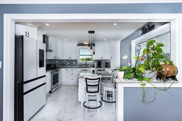 kitchen with stainless steel stove, decorative backsplash, refrigerator with glass door, white cabinetry, and wall chimney range hood