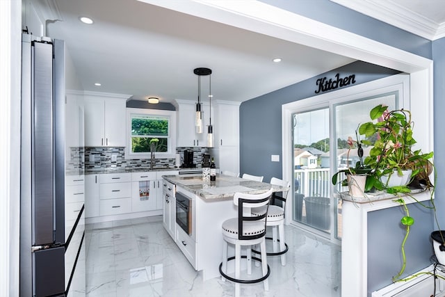 kitchen with white cabinetry, tasteful backsplash, decorative light fixtures, a center island, and a breakfast bar