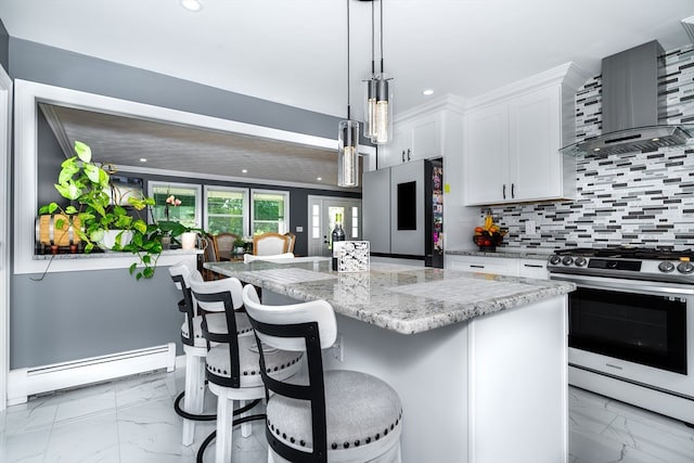 kitchen featuring a baseboard radiator, appliances with stainless steel finishes, a center island, white cabinetry, and wall chimney range hood