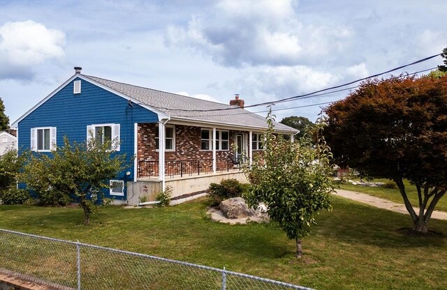 view of front of home with covered porch, fence, a front lawn, and brick siding