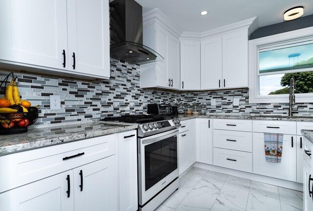 kitchen featuring marble finish floor, decorative backsplash, stainless steel gas stove, a sink, and wall chimney exhaust hood