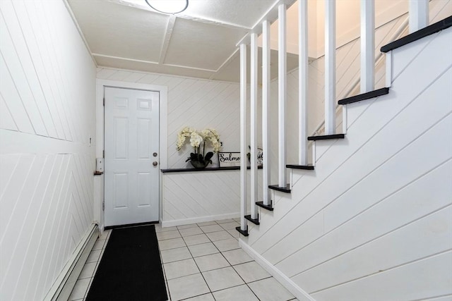 foyer with light tile patterned floors, a baseboard radiator, and stairs