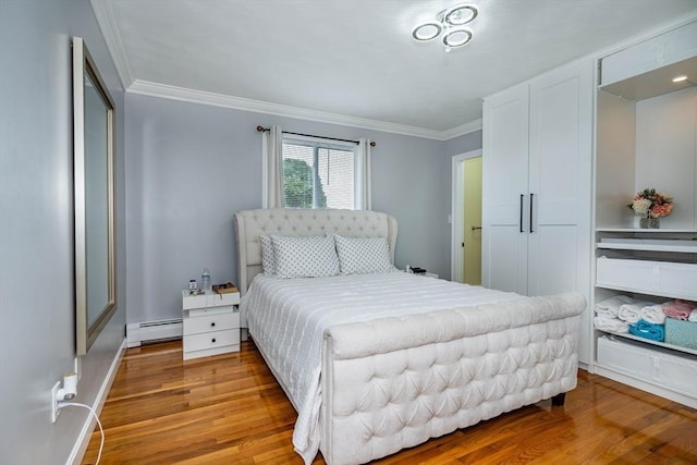 bedroom featuring ornamental molding, a baseboard radiator, and wood finished floors