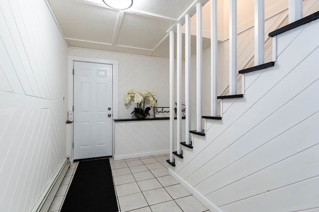 tiled foyer entrance featuring baseboard heating and wood walls