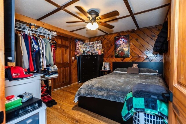 bedroom featuring wooden walls, a ceiling fan, and wood finished floors