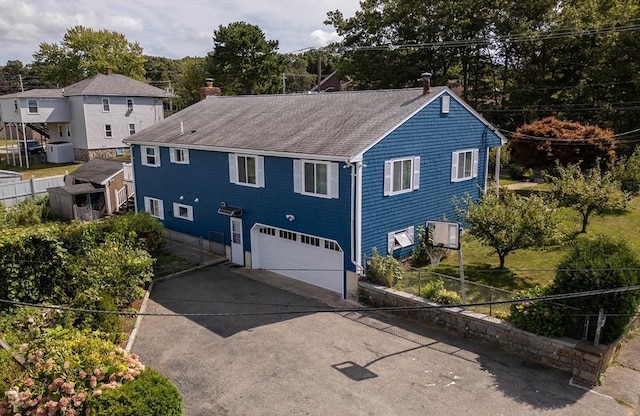 view of front facade with central AC unit, concrete driveway, a chimney, roof with shingles, and an attached garage