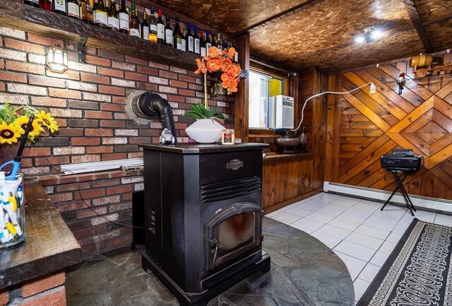 interior space with a wood stove, wood walls, brick wall, and baseboard heating