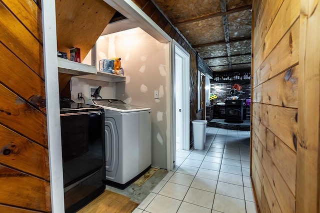 clothes washing area featuring light tile patterned floors, laundry area, hookup for a washing machine, and a wood stove