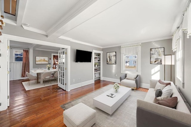 living room featuring beam ceiling, crown molding, a healthy amount of sunlight, and light wood-type flooring