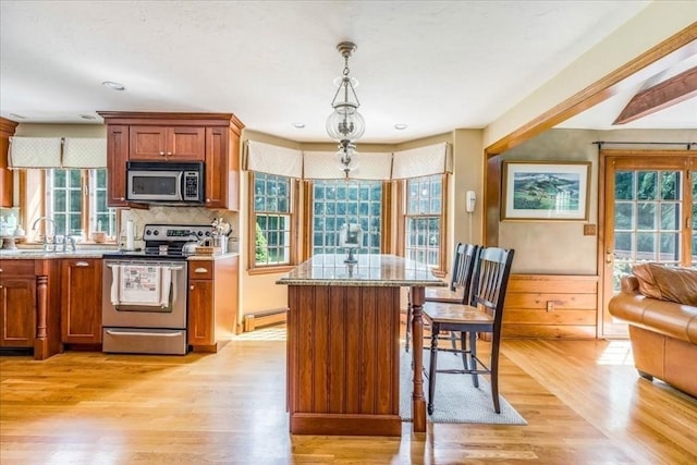 11 Tara Dr, Pembroke, MA 02359 - kitchen with appliances with stainless steel finishes, light wood-type flooring, a kitchen island, backsplash, and a breakfast bar area