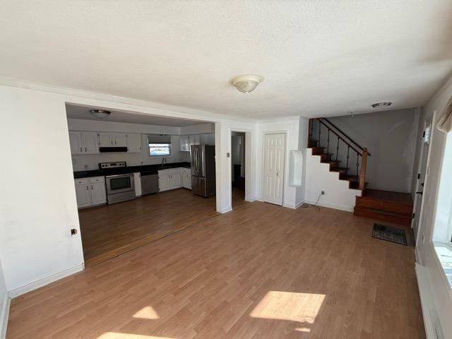 unfurnished living room with light wood-type flooring and a textured ceiling