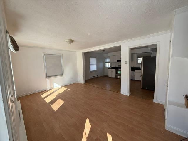 interior space featuring baseboard heating, a textured ceiling, dark hardwood / wood-style floors, and ornamental molding