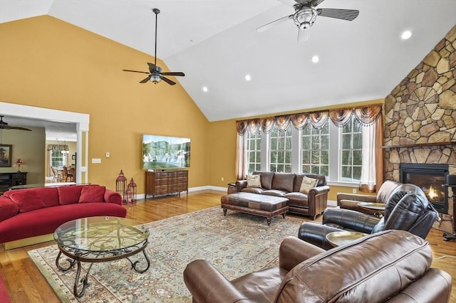 living room featuring ceiling fan, a fireplace, wood finished floors, and baseboards