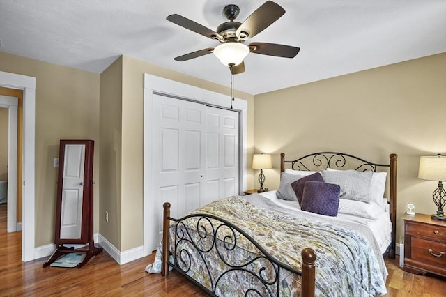 bedroom with a closet, ceiling fan, baseboards, and wood finished floors