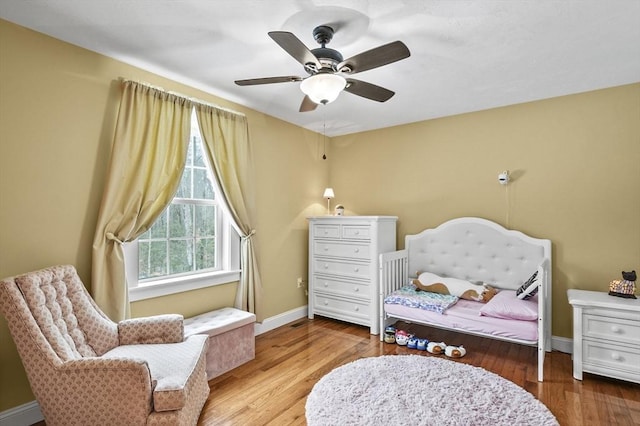 sitting room with a ceiling fan, baseboards, and wood finished floors