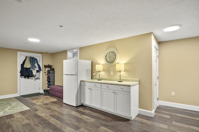 kitchen featuring baseboards, light countertops, dark wood-style flooring, and freestanding refrigerator