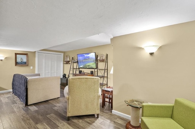 living room with a textured ceiling, baseboards, and wood finished floors